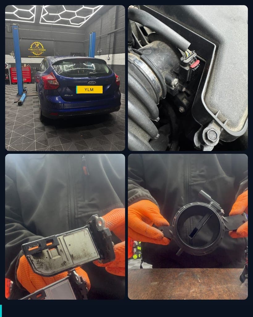 A blue Ford Focus on the ramp in the Dudley workshop, the air mass meter plugged into the intake beside the air filter housing, the old meter held up with dirt on its casing, and the meter housing on the bench